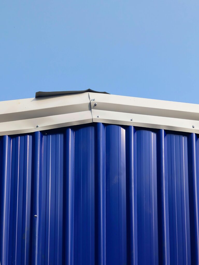 A detailed image of the roof edge of a blue metal building against a clear sky.